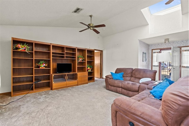 living room featuring carpet floors, ceiling fan, and vaulted ceiling with skylight