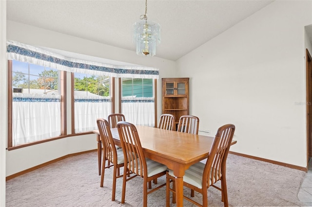 carpeted dining area with lofted ceiling and a notable chandelier