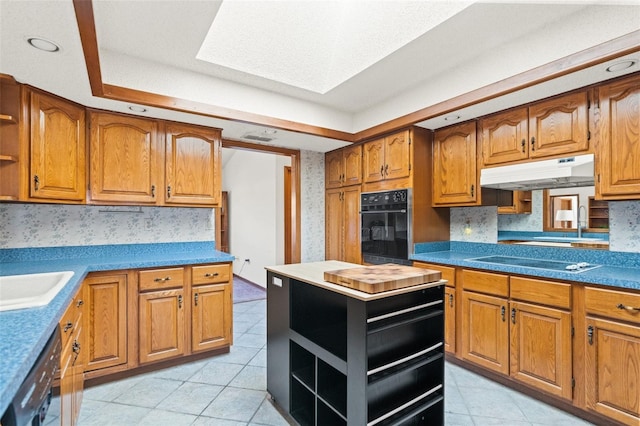 kitchen with decorative backsplash, a skylight, cooktop, dishwasher, and oven