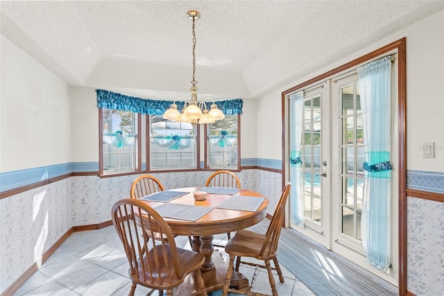 dining area with a raised ceiling, french doors, a textured ceiling, and a notable chandelier