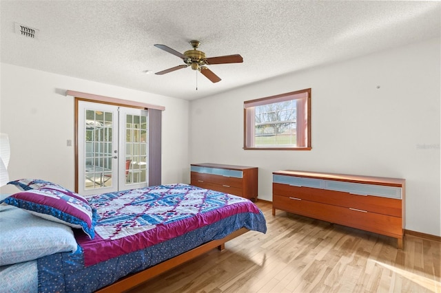 bedroom with access to exterior, ceiling fan, french doors, light hardwood / wood-style flooring, and a textured ceiling