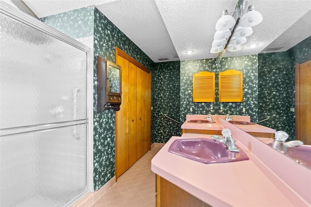 bathroom with vanity, a textured ceiling, tile patterned floors, and a shower with door