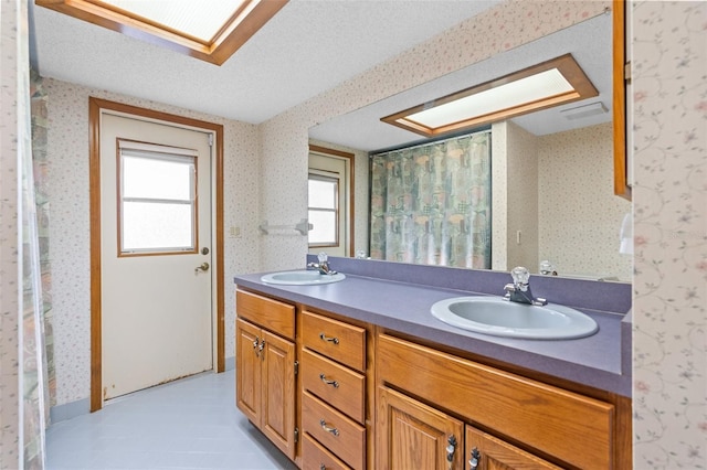 bathroom with a skylight, vanity, and a textured ceiling