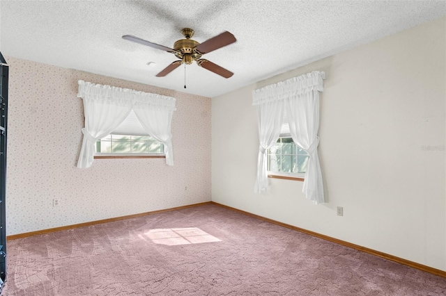 unfurnished room with carpet, ceiling fan, a textured ceiling, and a wealth of natural light