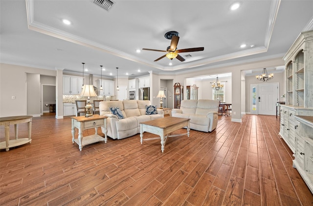 living room with ceiling fan with notable chandelier, a raised ceiling, and crown molding