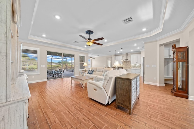 living room with ceiling fan, light hardwood / wood-style floors, a raised ceiling, and crown molding