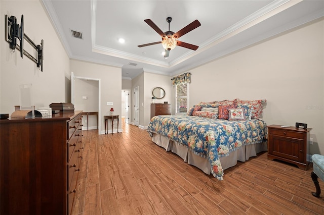 bedroom with a raised ceiling, ceiling fan, wood-type flooring, and ornamental molding