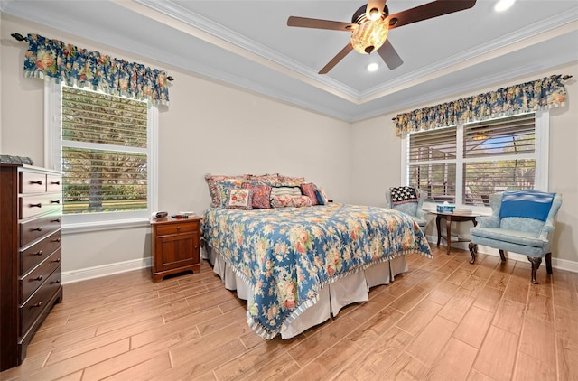 bedroom with ceiling fan, light wood-type flooring, ornamental molding, and a tray ceiling