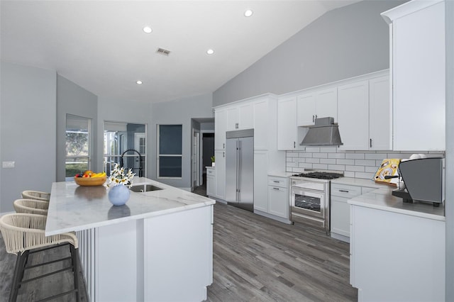 kitchen with an island with sink, white cabinets, decorative backsplash, and sink