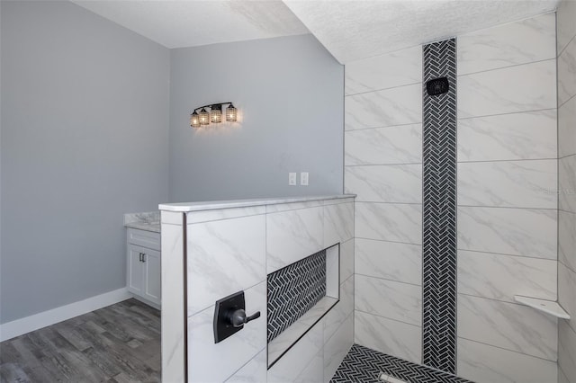 bathroom featuring vanity, wood-type flooring, and tiled shower