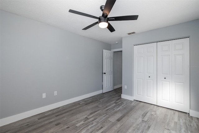 unfurnished bedroom with ceiling fan, a closet, and wood-type flooring