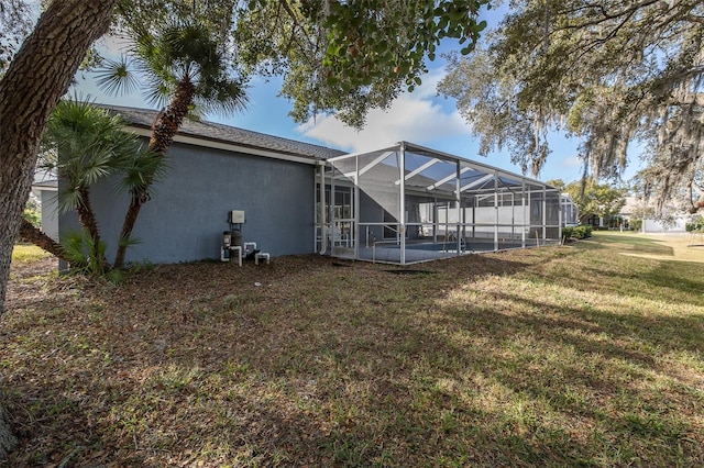 back of property with glass enclosure and a yard