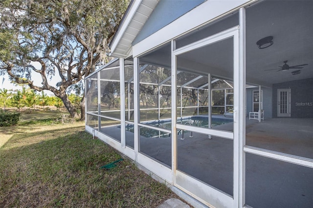 view of property exterior with glass enclosure, a patio area, a lawn, and ceiling fan