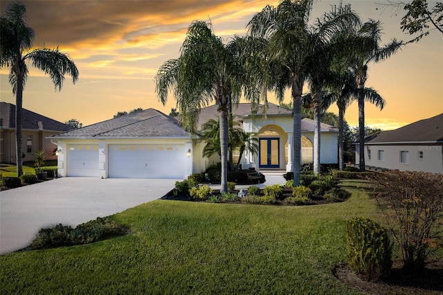 single story home featuring a lawn, a garage, and french doors