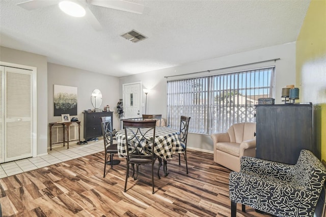 dining room featuring ceiling fan, light hardwood / wood-style floors, and a textured ceiling