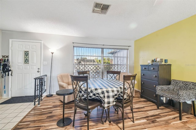 dining space with hardwood / wood-style floors and a textured ceiling