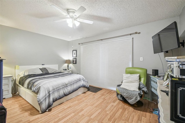 bedroom with ceiling fan, light hardwood / wood-style floors, and a textured ceiling