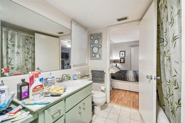 bathroom featuring tile patterned flooring, a textured ceiling, vanity, and toilet