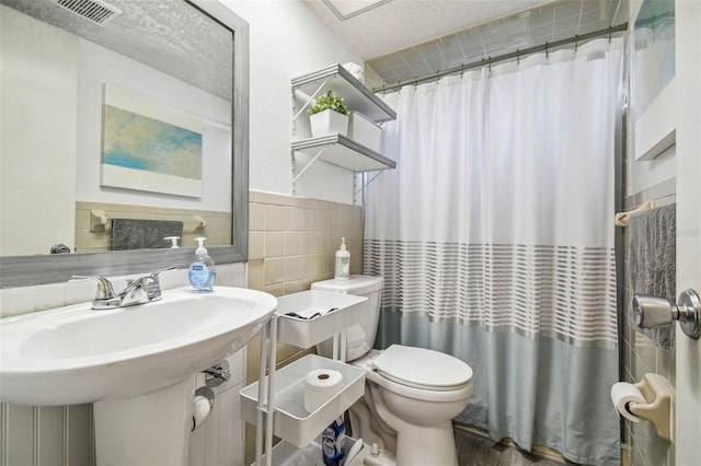 bathroom with a shower with shower curtain, sink, wood-type flooring, tile walls, and toilet