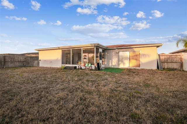 rear view of house with a lawn and a sunroom