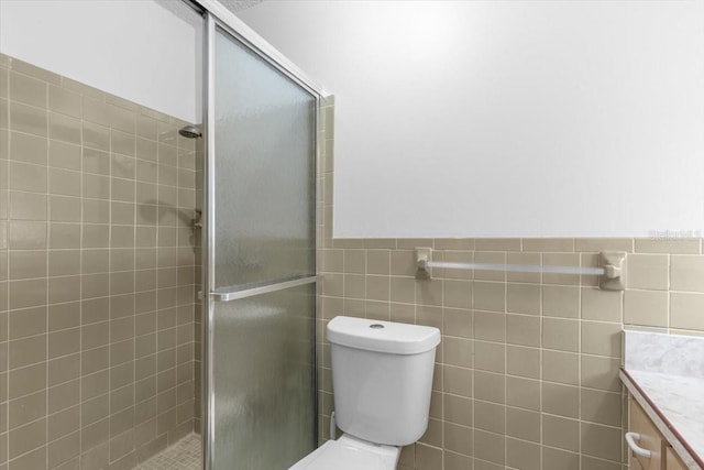 bathroom with toilet, vanity, tile walls, and walk in shower