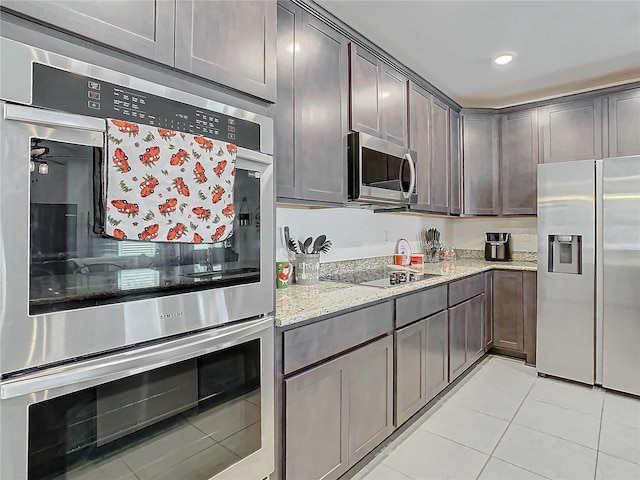 kitchen featuring ceiling fan, light stone countertops, appliances with stainless steel finishes, dark brown cabinets, and light tile patterned flooring