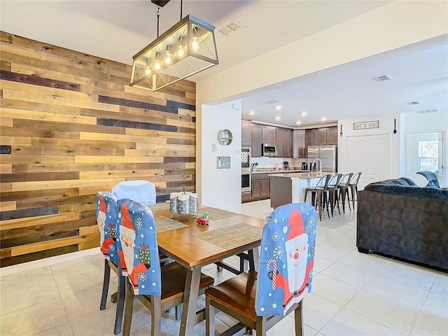 dining room featuring light tile patterned floors and wood walls