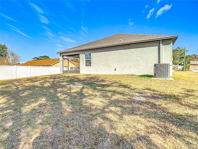 rear view of property with a yard and central AC unit