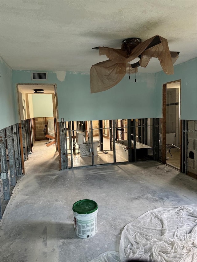 misc room featuring ceiling fan, concrete floors, and a textured ceiling