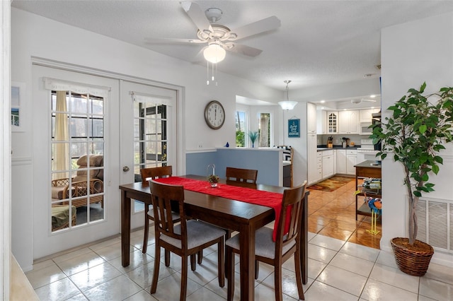 dining area featuring french doors, a textured ceiling, light tile patterned floors, and ceiling fan