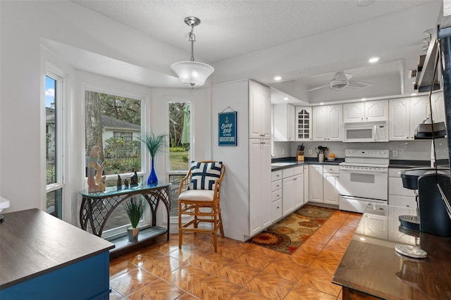 kitchen featuring white cabinetry, ceiling fan, hanging light fixtures, a textured ceiling, and white appliances