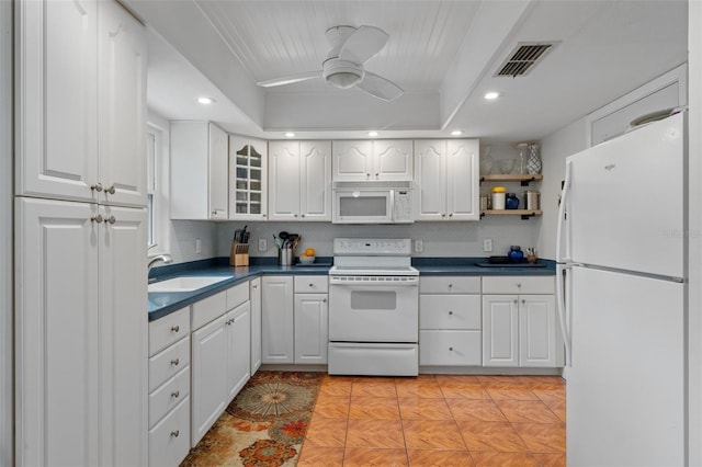 kitchen featuring white appliances, white cabinets, a raised ceiling, sink, and ceiling fan