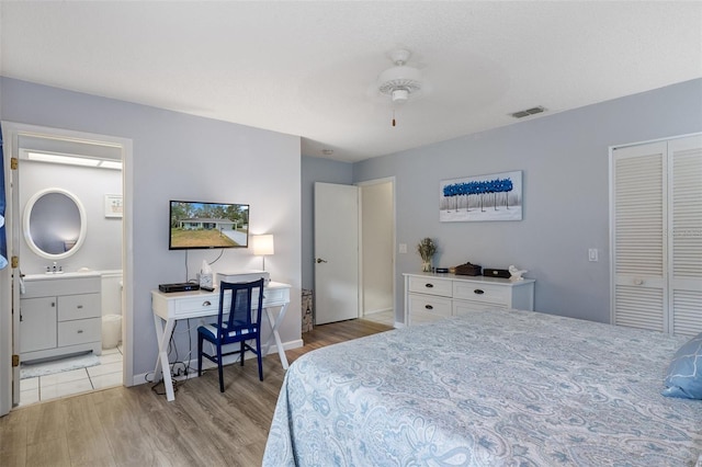 bedroom with connected bathroom, ceiling fan, a closet, and hardwood / wood-style flooring