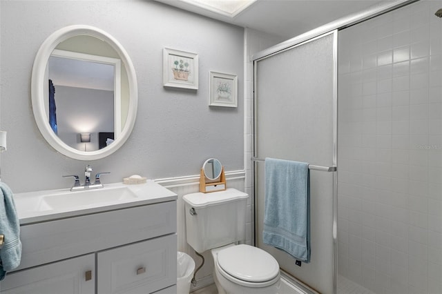 bathroom with vanity, toilet, and a shower with door