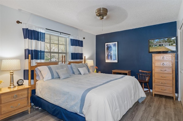 bedroom featuring ceiling fan, dark hardwood / wood-style flooring, and a textured ceiling