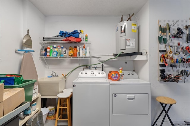 washroom featuring a workshop area, washing machine and clothes dryer, a textured ceiling, and water heater