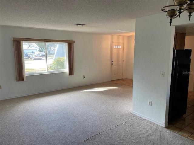 spare room featuring carpet floors, a textured ceiling, and a chandelier