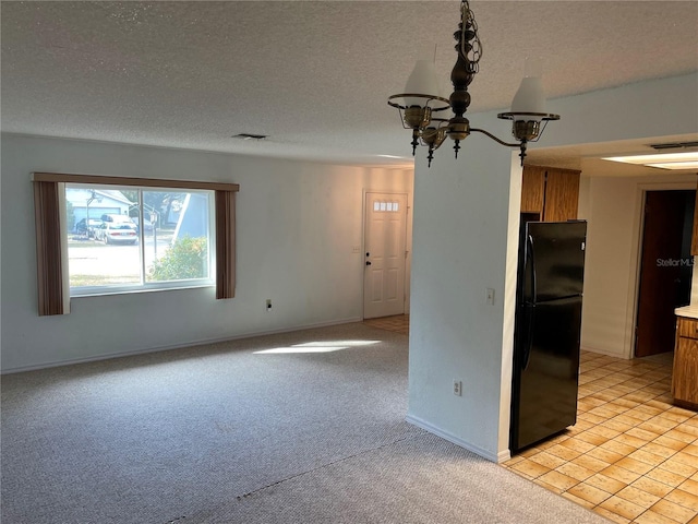 empty room with a notable chandelier, light colored carpet, and a textured ceiling