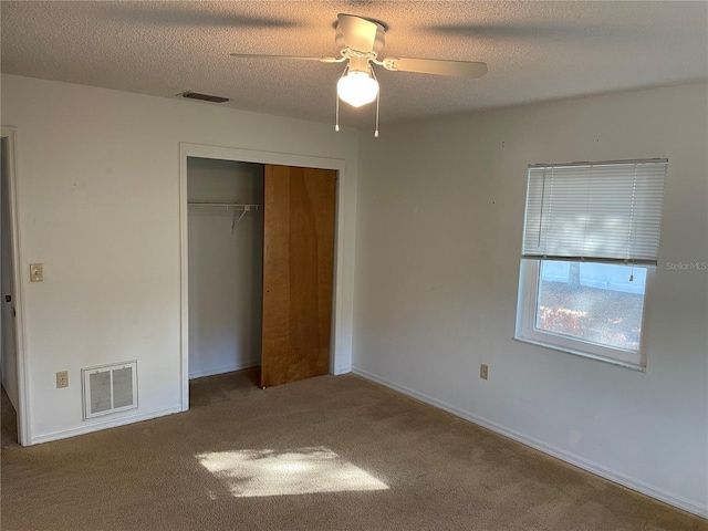 unfurnished bedroom featuring carpet, ceiling fan, a textured ceiling, and a closet