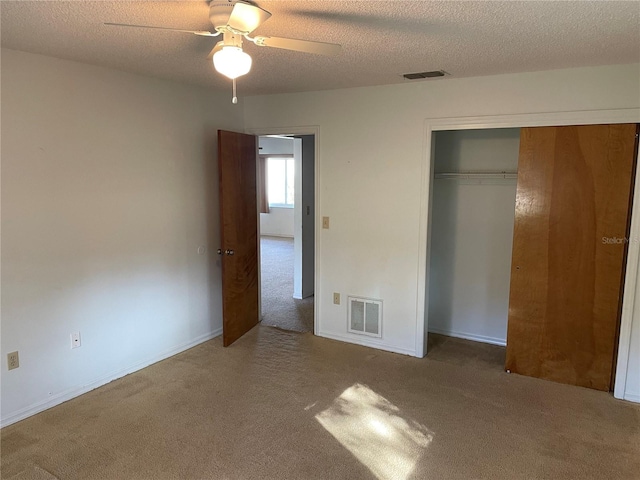 unfurnished bedroom with carpet, ceiling fan, a textured ceiling, and a closet