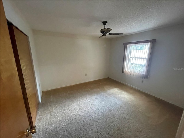 spare room featuring ceiling fan, light colored carpet, and a textured ceiling