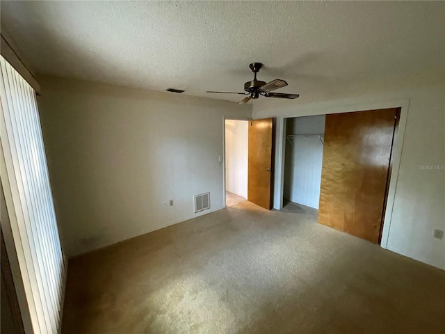 unfurnished bedroom with ceiling fan, a closet, light carpet, and a textured ceiling