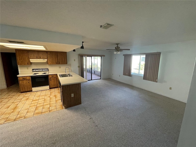 kitchen with ceiling fan, sink, white range, kitchen peninsula, and light carpet