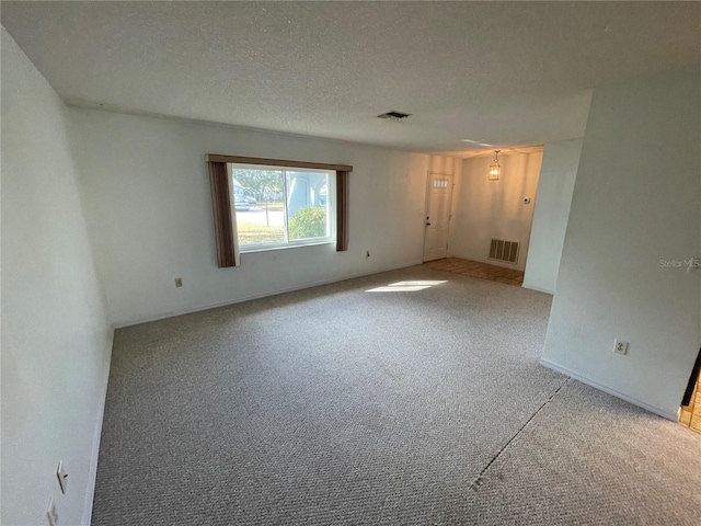 carpeted empty room with a textured ceiling