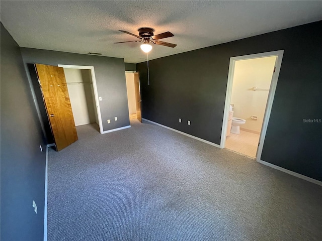 unfurnished bedroom featuring ensuite bath, ceiling fan, carpet floors, and a textured ceiling