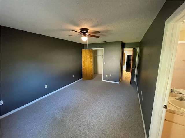 unfurnished bedroom featuring carpet, ensuite bath, a textured ceiling, ceiling fan, and sink