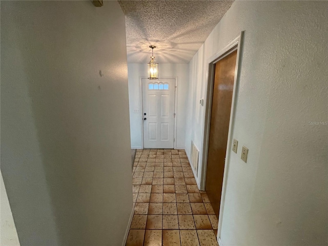 doorway with a textured ceiling and an inviting chandelier