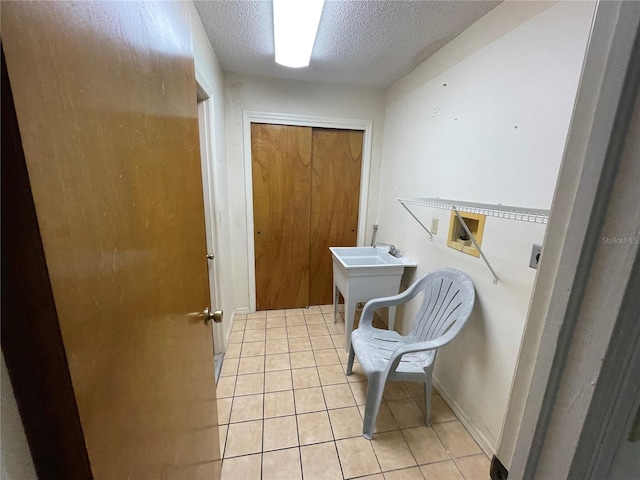 washroom featuring washer hookup, hookup for an electric dryer, light tile patterned flooring, and a textured ceiling