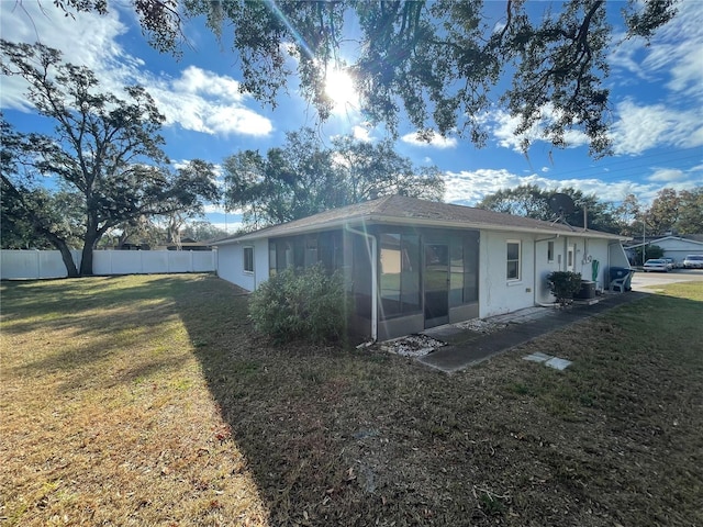 rear view of house with a sunroom and a lawn