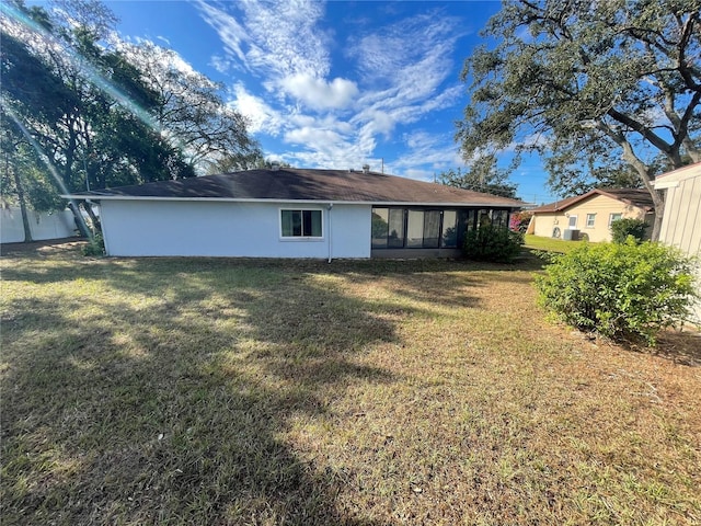 rear view of property with a lawn and a sunroom